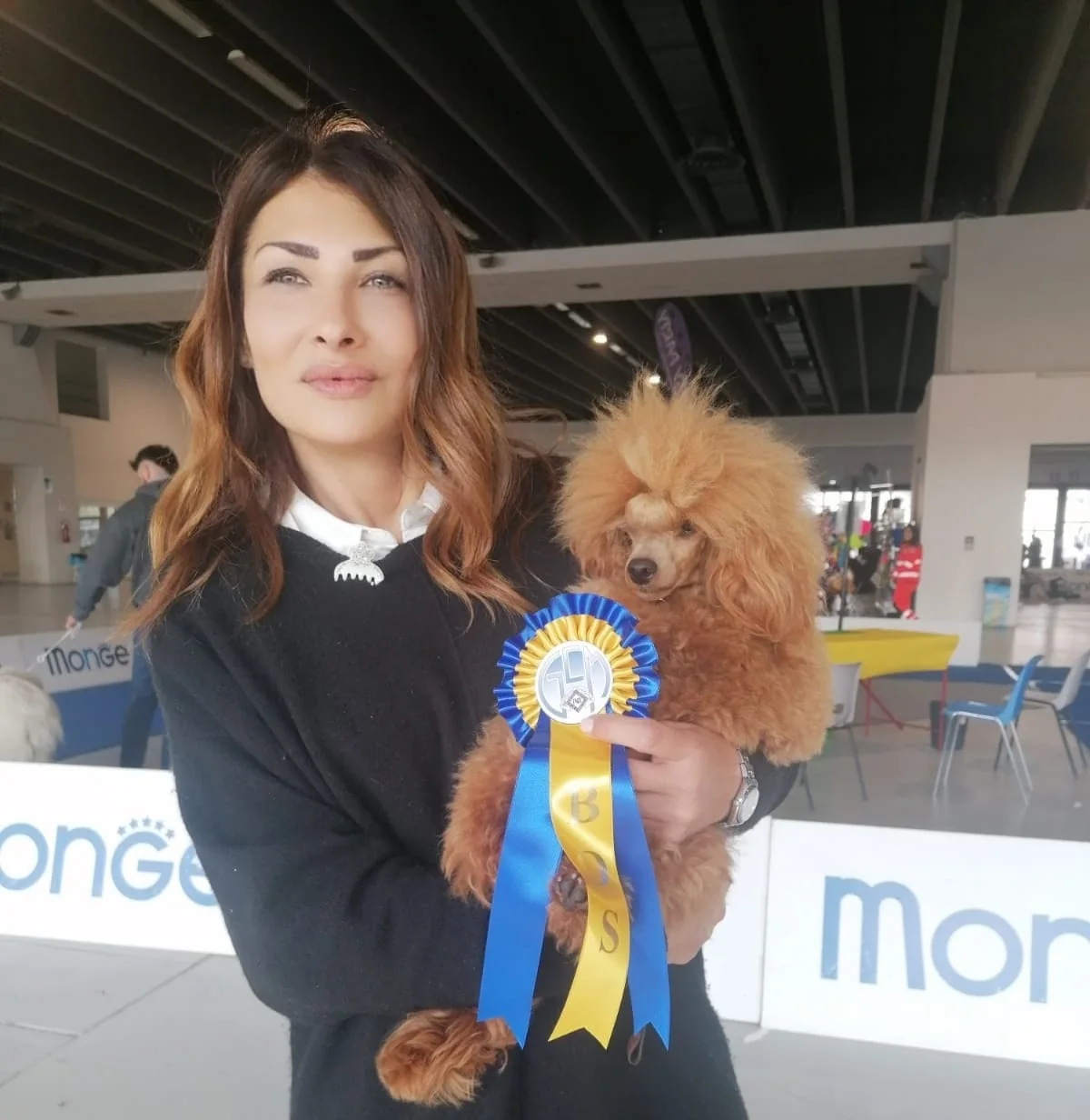 Owner holding poodle with award ribbon